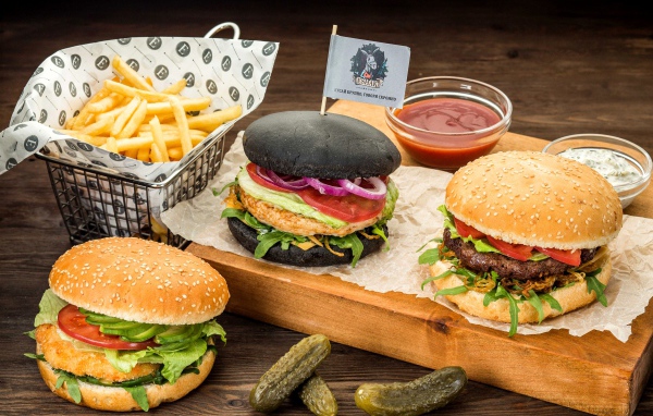 Гамбургеры с картофелем фри и солеными огурцами на столе 