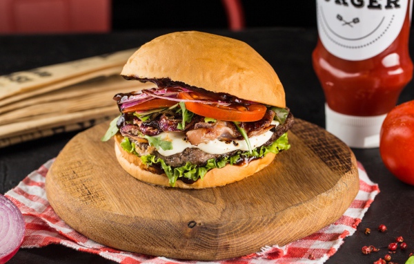 Большой аппетитный гамбургер на деревянной доске 