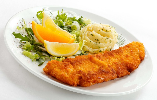 Картофельное пюре с мясом, кусочками апельсина и салатом на тарелке