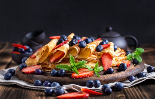 Блинчики с ягодами черники и клубники на столе