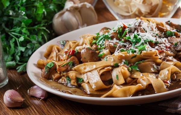 Паста с грибами, сыром и  зеленью на столе с чесноком 
