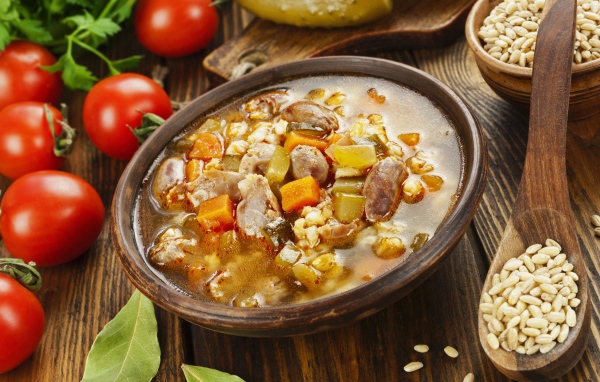 Перловый суп с сердечками на столе с помидорами 