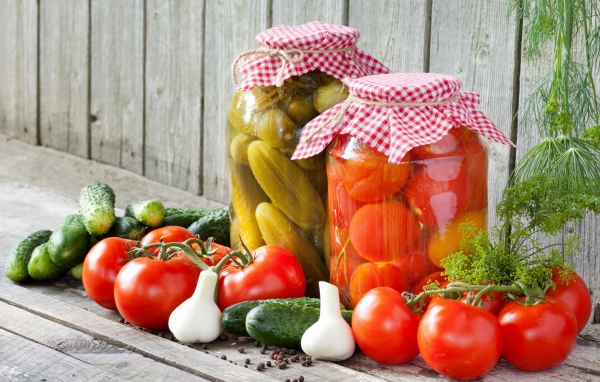 Соленья из огурцов и помидоров с овощами на столе