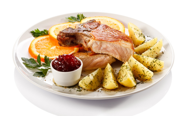 Картофель с мясом и кусочками апельсина на тарелке