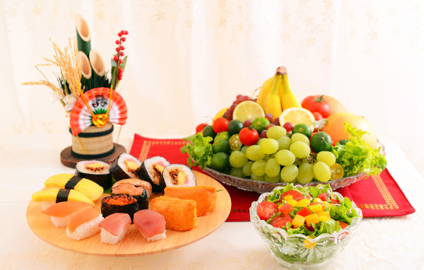 Роллы на столе с овощным салатом и фруктами 