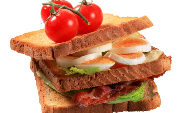 Сэндвич с яйцами, беконом и помидорами на белом фоне