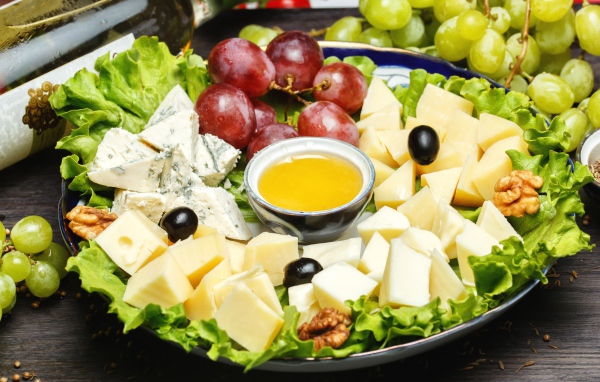 Нарезанный сыр на тарелке в виноградом 