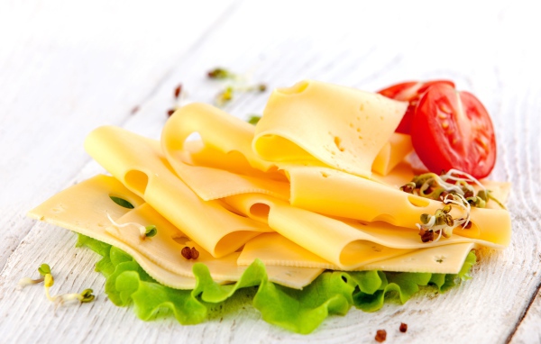 Тонко нарезанный сыр с листом салата и помидором