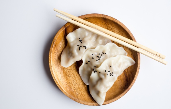 Три вареника на деревянной тарелке с палочками