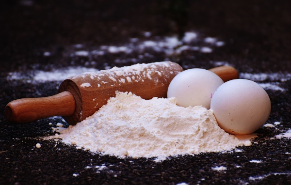 Два яйца, мука и скалка на столе