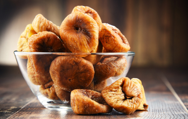 Инжир в стеклянной вазе на столе 