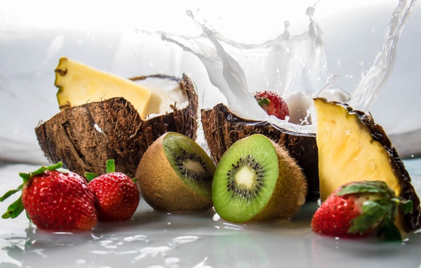 Тропические фрукты кокосы, ананасы и киви на белом фоне с клубникой