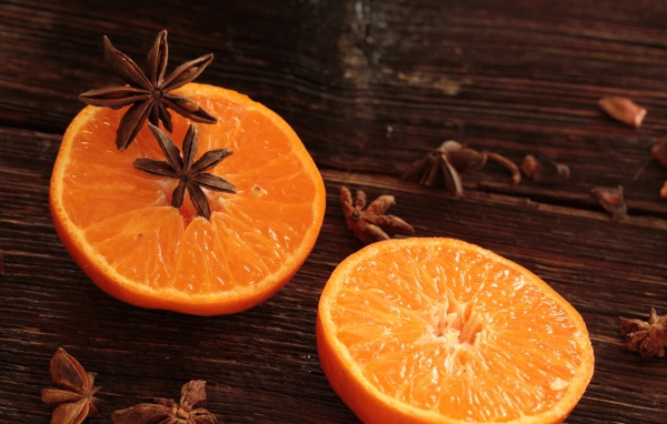 Две половины апельсина на деревянном столе с бадьяном