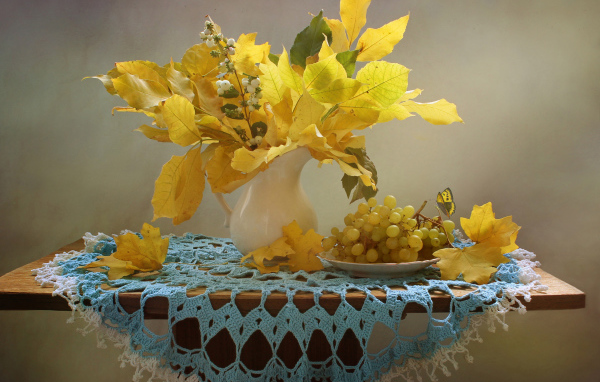 Белый виноград на столе с желтыми осенними листьями
