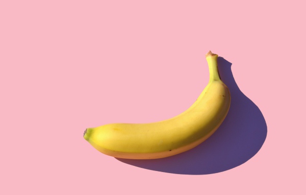 Желтый банан на розовом фоне