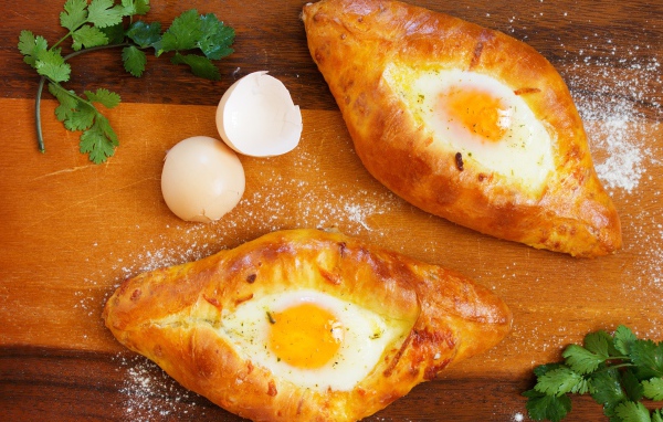 Две булки с яйцом, скорлупой и зеленью на столе