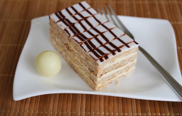 Кусок торта на белой тарелке с вилкой и конфетой 