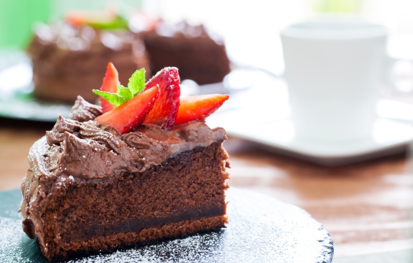 Кусок пирога с шоколадным кремом и кусочками спелой клубники 