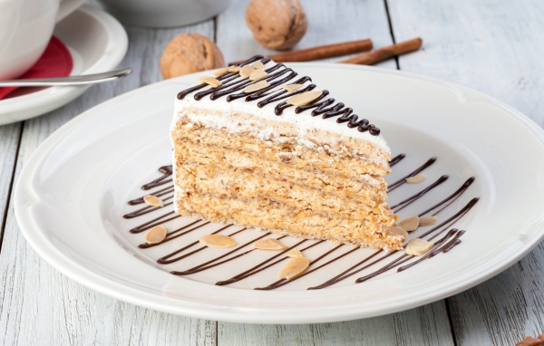 Кусок торта с орехами и шоколадом на белой тарелке