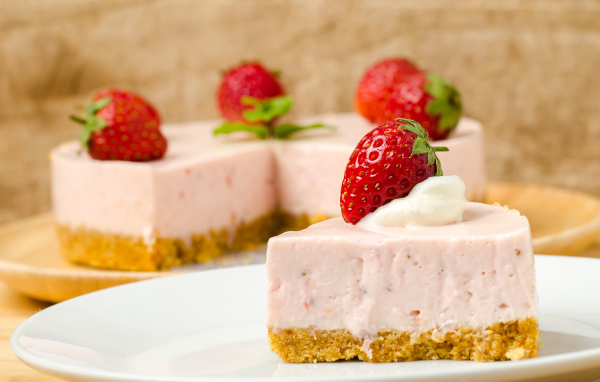 Кусок торта с клубникой на белой тарелке