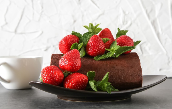 Кусок шоколадного торта со свежей клубникой на тарелке