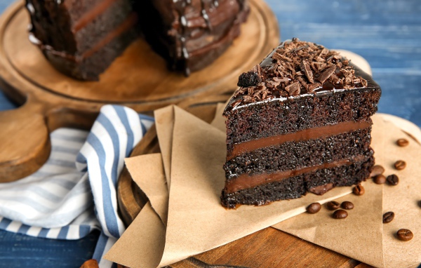 Кусок вкусного шоколадного торта на столе с кофейными зернами