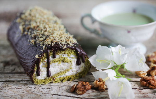 Аппетитный сладкий рулет с шоколадом на столе с белыми цветами колокольчика