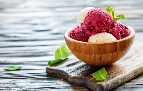 Шарики фруктового и ванильного мороженого в деревянной миске на столе