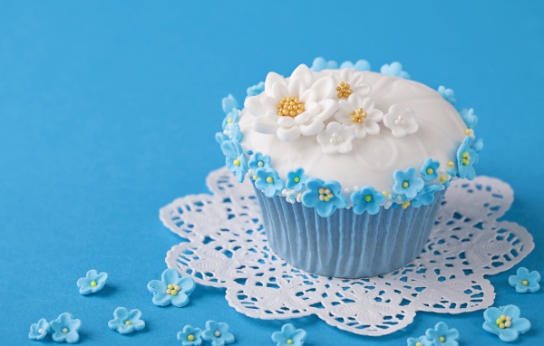 Красивый кекс украшен сахарными цветами на голубом фоне