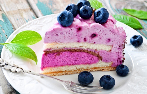 Торт с черничным муссом и свежими ягодами черники на белой тарелке 