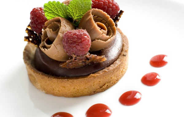 Пирожное с шоколадом и ягодами малины на белом фоне