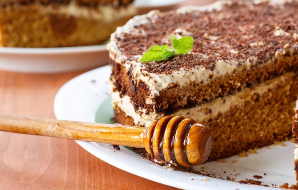 Торт с кремом и шоколадом на тарелке с ложкой для меда