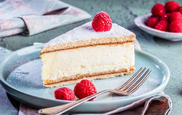 Чизкейк с сахарной пудрой и ягодами малины на тарелке