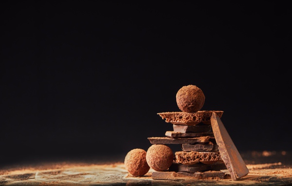 Шоколадные шарики и кусочки шоколада на черном фоне