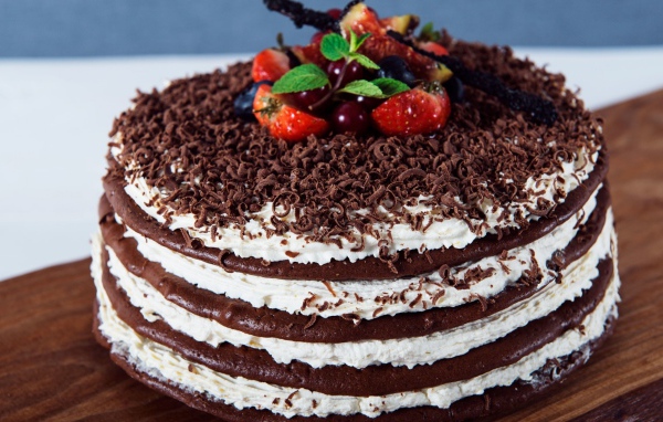 Шоколадный торт с кремом и тертым шоколадом украшен ягодами