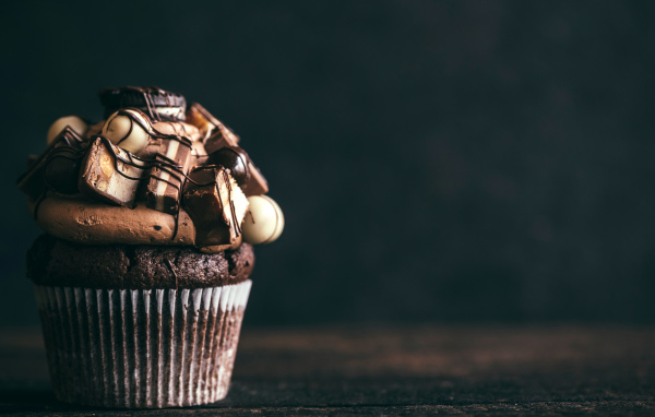 Шоколадный кекс с кремом и конфетами на сером фоне