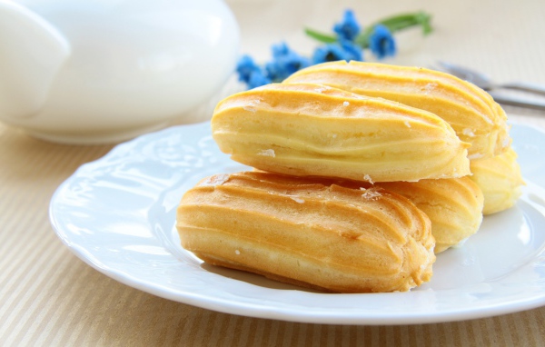 Заварные пирожные на большой белой тарелке 