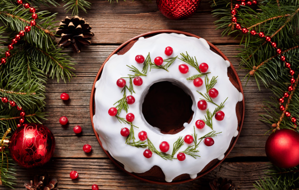 Рождественский пирог с ягодами клюквы на деревянном столе с еловыми ветками