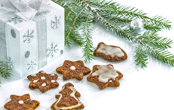 Новогоднее печенье с подарком и еловой веткой на белом фоне