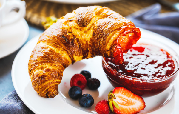 Круассан с джемом и ягодами на тарелке