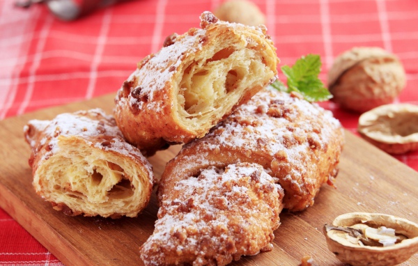 Croissants with nuts and powdered sugar on a cutting board