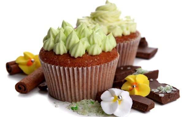 Кексы с кремом, шоколадом и корицей на белом фоне