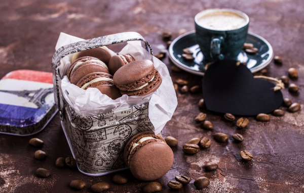 Десерт макарон на столе с кофейными зернами и чашкой кофе