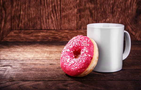 Пончик с белой кружкой на деревянном столе