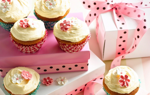 Праздничные кексы с кремом и подарочной коробкой на столе