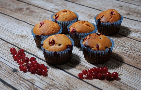 Свежие кексы с красной смородиной на деревянном столе 