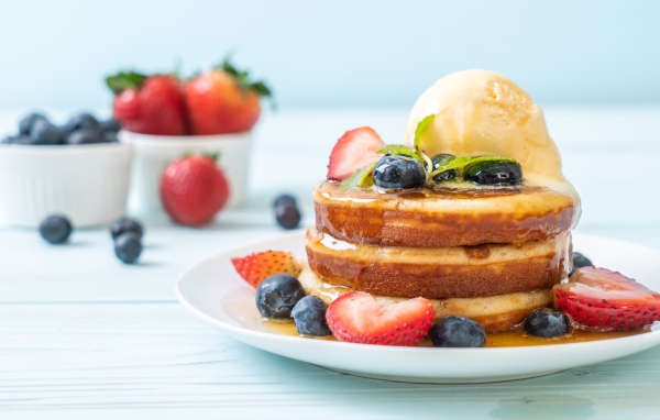 Оладья и медом, мороженым и ягодами черники и клубники на столе