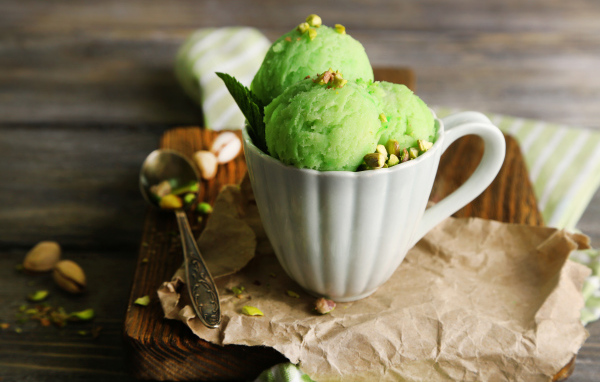 Фисташковое мороженое в белой чашке на столе