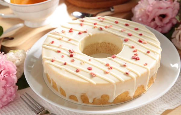 Круглый кекс с глазурью на белом блюде 