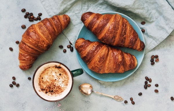Три круассана на столе с чашкой кофе